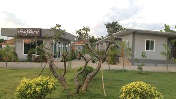 A modern building with a sign in a foreign language, surrounded by well-maintained grass and small trees.