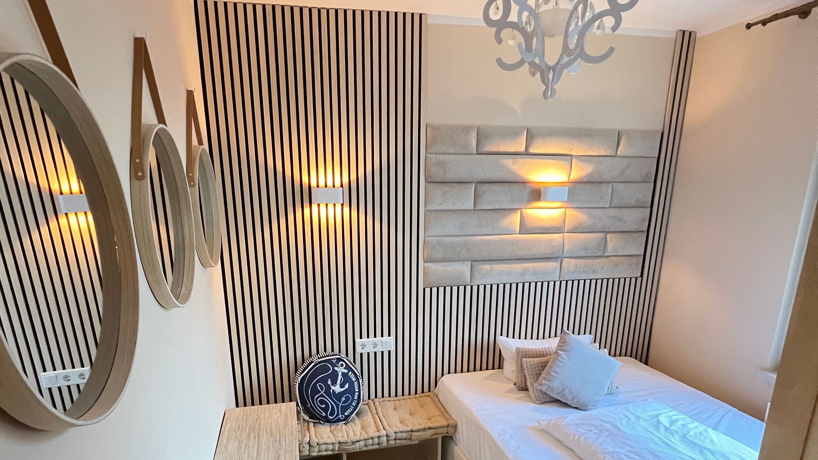 Une chambre à coucher comprenant un lit, une table de chevet, un panneau décoratif mural et un luminaire fixé au mur.