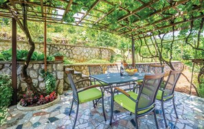 A covered outdoor patio with a stone wall, a mosaic floor, and a table with chairs. - Beach front apartment in Lovran (Lovran)