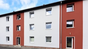 Un edificio de varios pisos con fachada roja y blanca, múltiples ventanas y puertas.