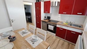 Una cocina compacta con armarios rojos, horno empotrado y microondas.
