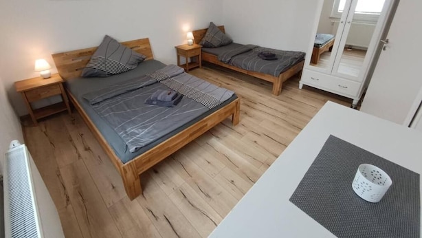 Un dormitorio con dos camas de madera, un escritorio blanco y un armario.