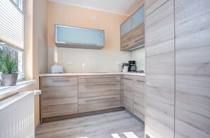 A modern kitchen with wooden cabinets, a built-in microwave, and a coffee maker.