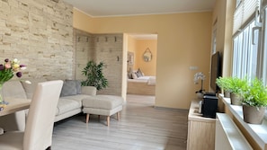 Een moderne woonkamer met een hoekbank, een eettafel en een groot raam.