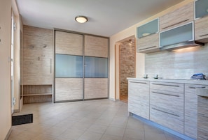 Een moderne keuken met houten kastjes, een inbouwoven en een accentmuur van steen.