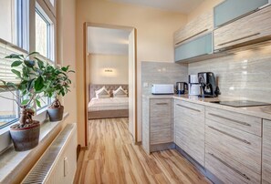 A modern kitchen with built-in appliances, a radiator, and a potted plant.