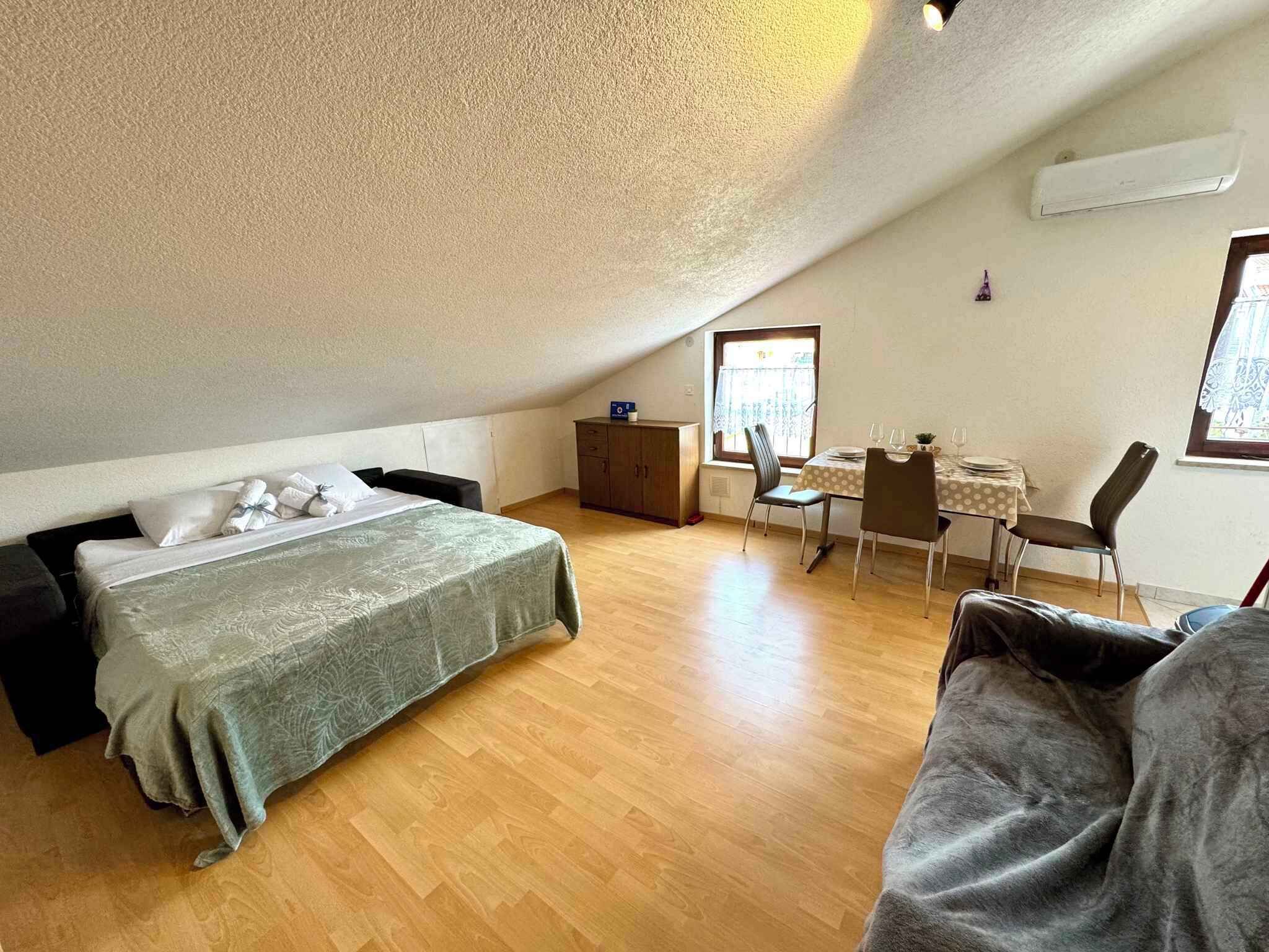 A bedroom with a bed, a small desk, and a dining table with chairs.