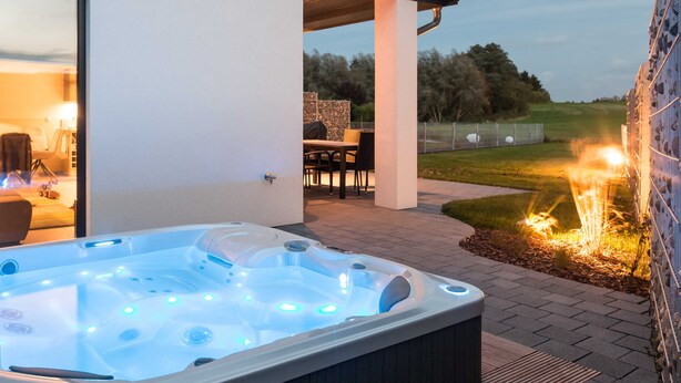 A hot tub with multiple jets, a patio area with outdoor furniture, and a fire feature.