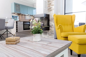 A modern living room with a wooden coffee table, a white vase with flowers, and a yellow armchair.