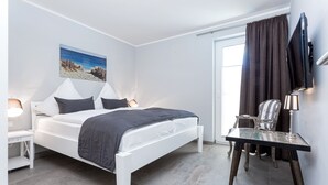 A modern bedroom with a bed, bedside tables, a desk, and a television.