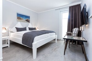 A modern bedroom with a bed, bedside tables, a desk, and a television.