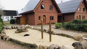 Ein Backsteinhaus mit einem Kiesweg, einem Holzpfosten und einer Sandkiste.