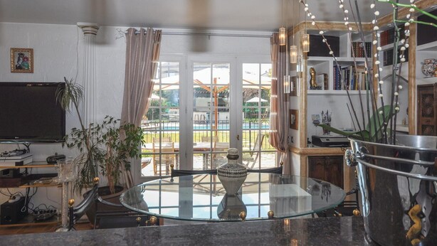 Una sala de estar moderna con una mesa de centro de vidrio, un televisor de pantalla plana y una estantería.