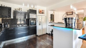 Una cocina moderna con una isla central, electrodomésticos integrados e iluminación colgante.