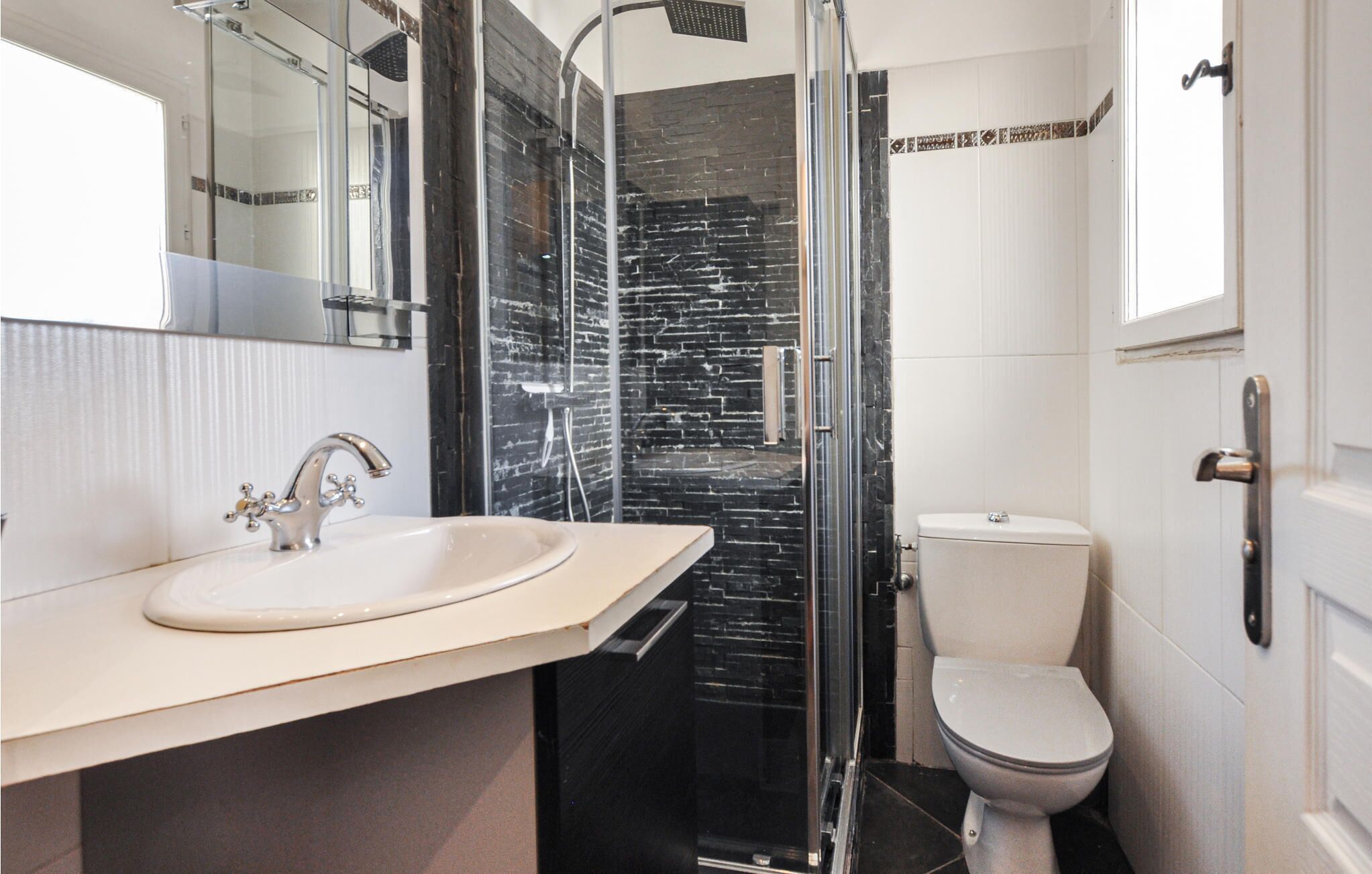 A modern bathroom with a large sink, a glass shower enclosure, and a toilet.