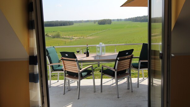 A balcony with a table set for two, chairs, and a bottle of wine. - House BELLEVUE upper floor (Göhren-Lebbin)