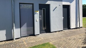 A modern building with three doors, a metal gutter, and a paved entrance area. - House BELLEVUE upper floor (Göhren-Lebbin)