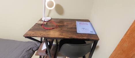A small wooden desk with a ring light, a power strip, and a welcome sign for Koto Inn.