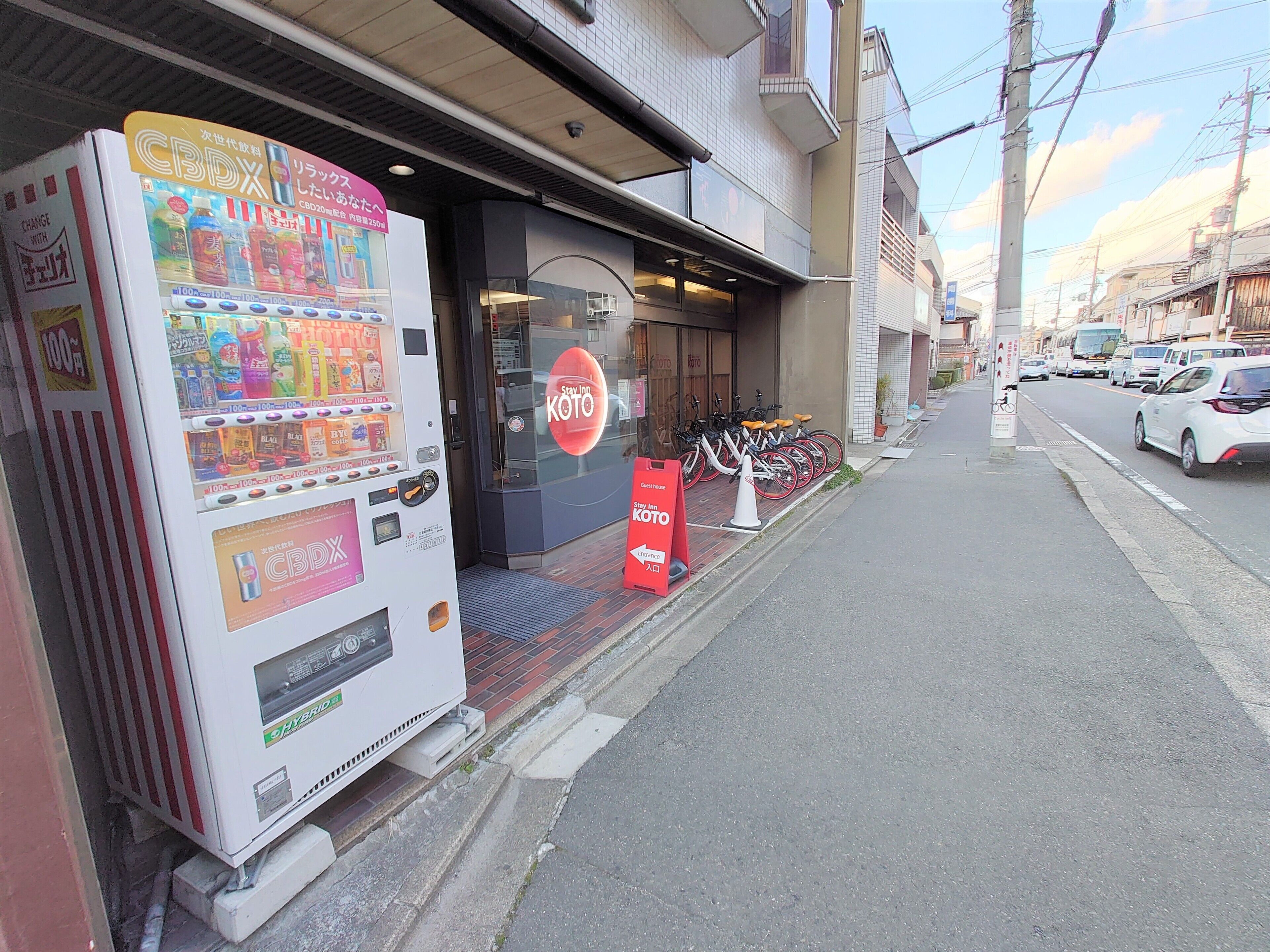 A hotel entrance with a bicycle parking area and a vending machine.