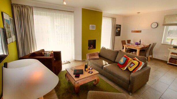 Una sala de estar con sofá, una mesa de centro, una lámpara y un comedor con sillas y una mesa.