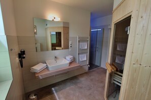A modern bathroom with a sink, mirror, and towel rack.