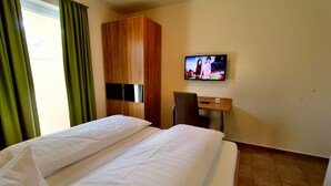 Habitación de hotel con dos camas, un televisor en la pared y un armario de madera.