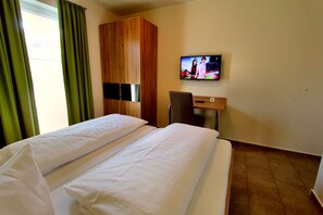 Una camera d'albergo con due letti, una televisione a parete e un armadio in legno.