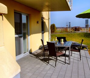 An outdoor patio with a table and chairs, a bottle of champagne, and a candle.