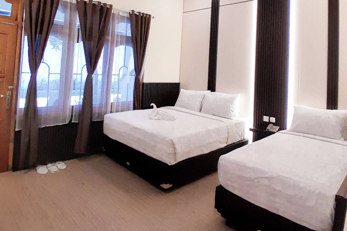A hotel room with two beds, a wooden door, and a view through the window.