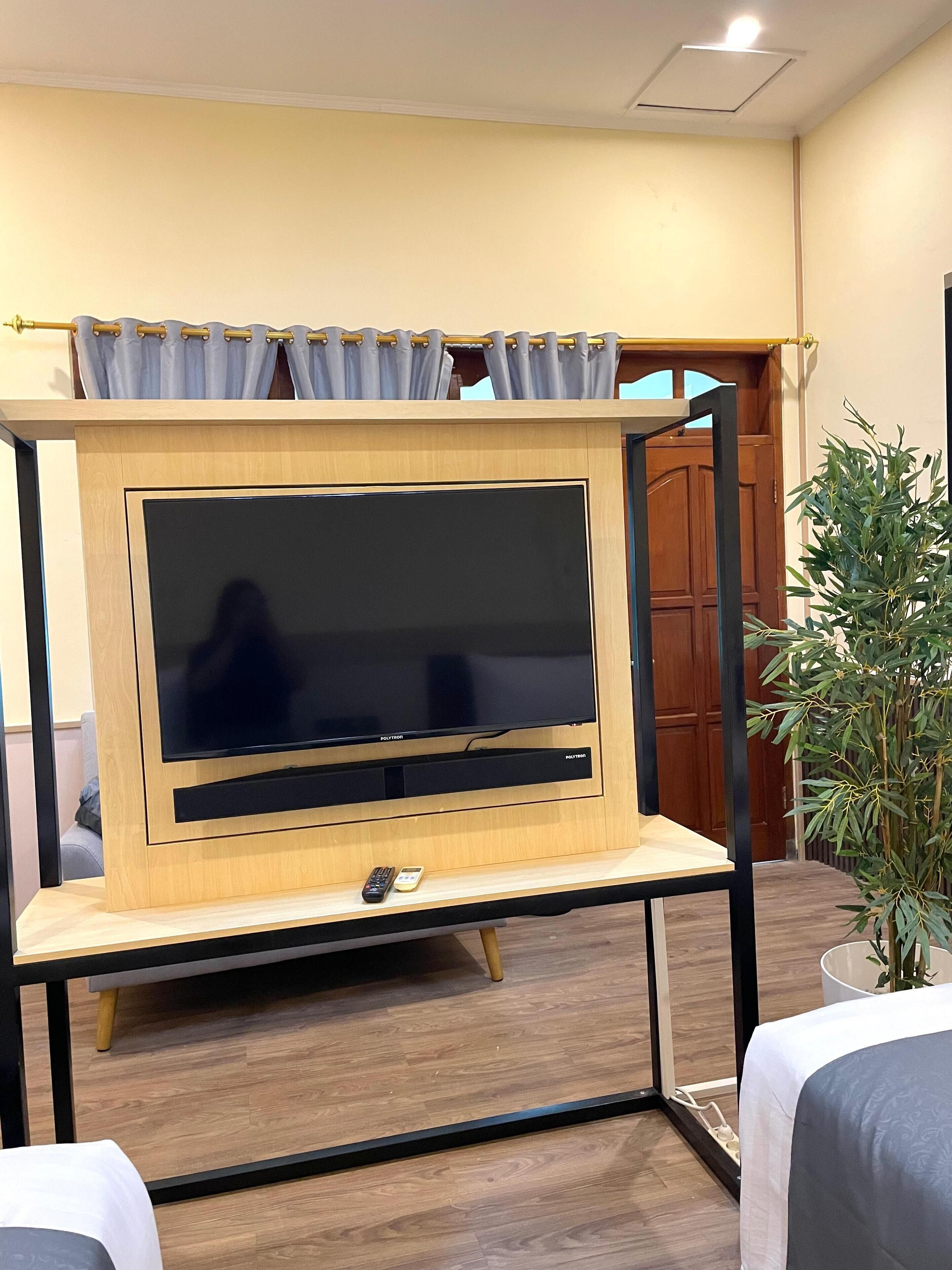 A TV mounted on a wooden stand with a remote control on the stand.