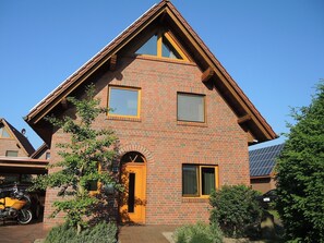 A two-story house with a brick facade, a prominent gabled roof, and a front door with a small porch. - Suite Anna with terrace 25 u (SA) - Usedom Suites 25***, beach 100 m (Karlshagen)