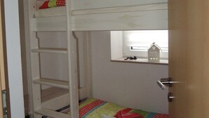 Uma cama de solteiro com janela sobre a cama inferior.