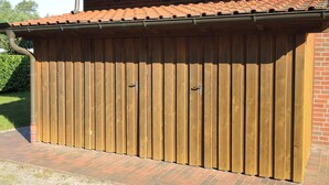 Uma garagem de madeira com telhado de telhas e parede de tijolos.