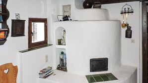 Una habitación rústica con una silla de madera, un pequeño armario de madera, una estantería con libros y un adorno en la pared.