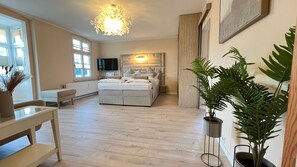 Ein Schlafzimmer mit einem großen Bett, einem Nachttisch, einem Fernseher und einem Fenster.