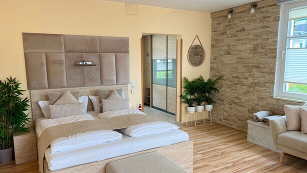 Quarto com uma cama grande, um sofá, uma parede de pedra e uma janela.