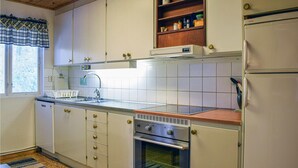 A kitchen with white cabinets, a stainless steel sink, a built-in oven, and a refrigerator. - 1 bedroom awesome home in Simrishamn (Simrishamn)