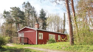 A red wooden cabin with a chimney, surrounded by trees and a grassy area. - 1 bedroom awesome home in Simrishamn (Simrishamn)
