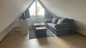 A small, sloped-roofed room with a sofa, a small table, and a radiator. - House 13 Ute (SA) - Usedom Suites House Ute and Baigle***, beach 100 m (Karlshagen)