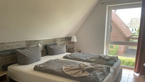 A bedroom with a large bed, a nightstand, a lamp, and a view of the outside. - House 13 Ute (SA) - Usedom Suites House Ute and Baigle***, beach 100 m (Karlshagen)