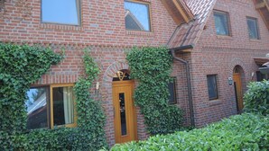 A brick building with a wooden door and windows, surrounded by greenery. - House 13 Ute (SA) - Usedom Suites House Ute and Baigle***, beach 100 m (Karlshagen)