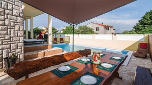 An outdoor dining area with a pool, stone walls, and a view of a house in the background. - Lovely home in Polaca (Polaca)