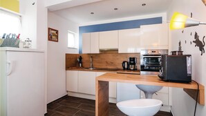 A compact kitchen with a wooden table, a white sink, and a modern oven. - Lovely home in Polaca (Polaca)