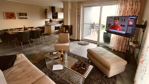 A modern living room with a sofa, coffee table, and a flat-screen TV displaying a sports channel.