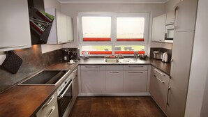 A modern kitchen with a built-in oven, a sink, and a window with a view of the outdoors.