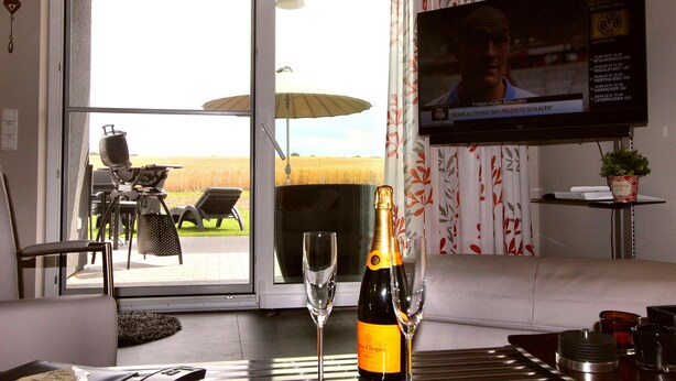 A room with a TV displaying a sports channel, a bottle of champagne, and a glass on a table.