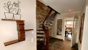 A staircase with a wooden finish and a stone wall.