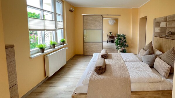 Une chambre d’hôtel avec un lit, un radiateur, une fenêtre avec des plantes et une vue sur la salle à manger.