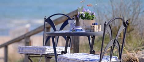 A metal table with a blue and white patterned tablecloth, a potted plant with flowers, and a small blue and white ceramic pot.