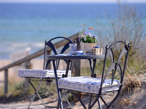 A metal table with a blue and white patterned tablecloth, a potted plant with flowers, and a small blue and white ceramic pot.